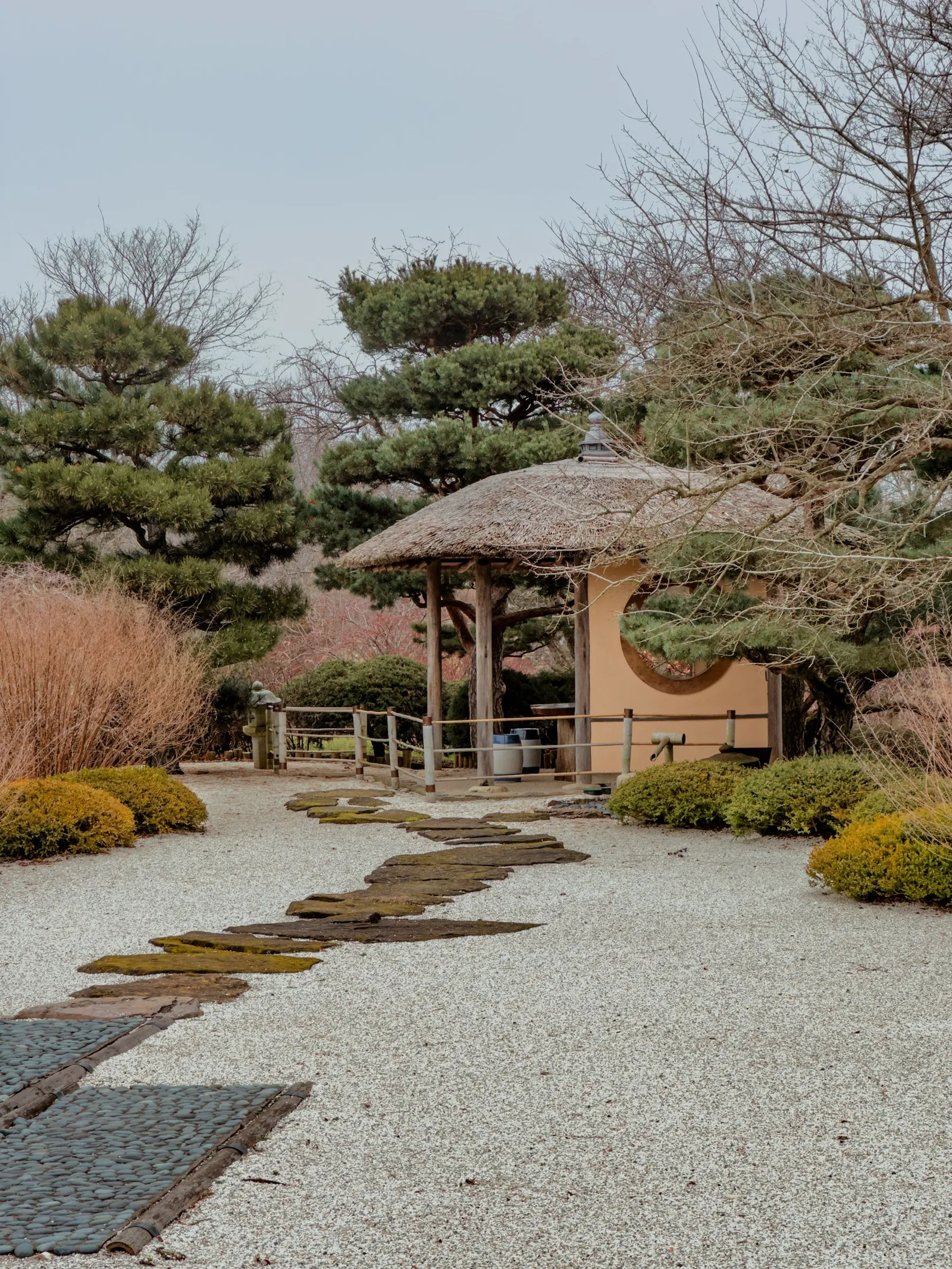 Thatched-roof pavilion in a garden with a gravel and stepping-stone path