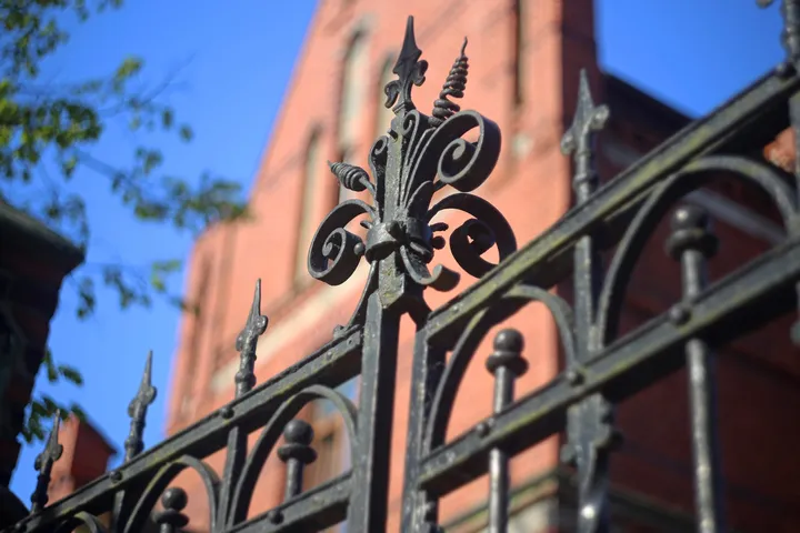 Detail of a wrought iron finial on a brick-framed fence